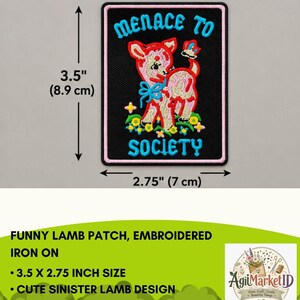 May include: A rectangular embroidered iron-on patch with a black background and pink border. It features a pink lamb with a blue bow, flowers, and a butterfly. The text reads "MENACE TO SOCIETY" in blue. It measures 3.5 inches by 2.75 inches.