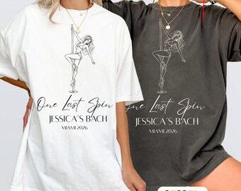 May include: Two oversized t-shirts, one white and one charcoal gray, each featuring a black line art graphic of a person on a pole. The text reads One Last Spin, JESSICA'S BACH, and MIAMI 2026. The shirts have short sleeves and a crew neckline.