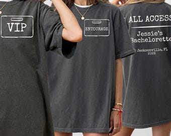 May include: A charcoal gray oversized t-shirt featuring white graphic prints. The front displays a rectangular badge with the text VIP or ENTOURAGE. The back features the text ALL ACCESS, Jessie's Bachelorette, and Jacksonville, FL 2026.