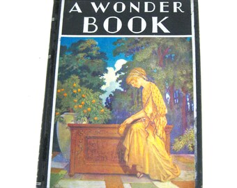 May include: A vintage book titled "A Wonder Book" with a black cover. The cover art depicts a woman in a yellow dress seated near a wooden chest in a garden setting. The background features trees and a blue sky.