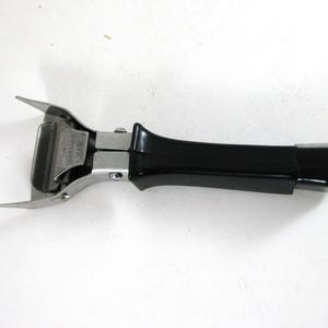 May include: A white ceramic mug with a black handle and the text "But First, Coffee" in a black, handwritten-style font. The mug is on a white surface.