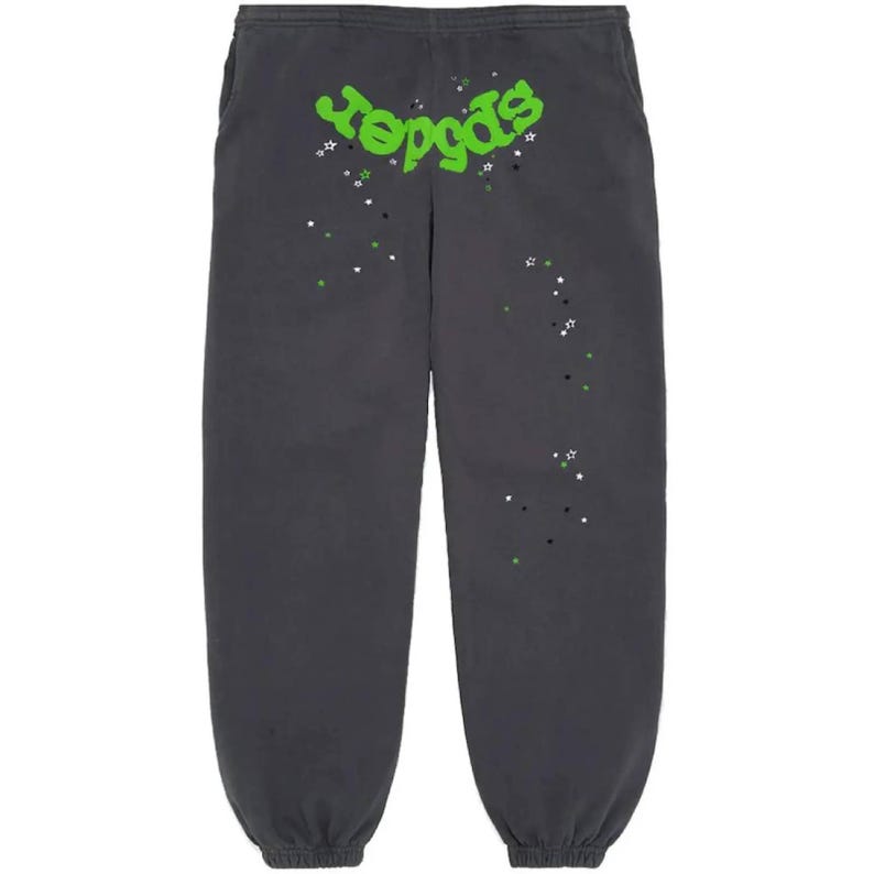 May include: Dark gray sweatpants with the word "reggas" in bright green, accented with white, green, and black star graphics. The sweatpants have an elastic waistband and cuffs, and pockets on the sides.
