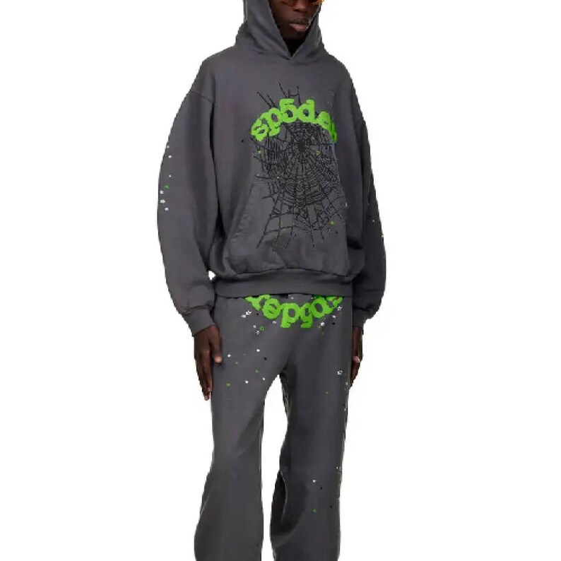 May include: A dark gray hoodie and matching pants set. The hoodie features a green spiderweb design and the word "sp5der" in green. The pants also have the word "sp5der" in green. Both pieces have white and silver splatter paint.