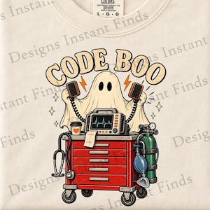 Puede incluir: Una camiseta color crema con un gráfico de un fantasma sosteniendo paletas de desfibrilador sobre un carro médico rojo. El carro contiene un monitor cardíaco con un trazado de ritmo, un estetoscopio, un café y un tanque de oxígeno. Texto: CODE BOO.