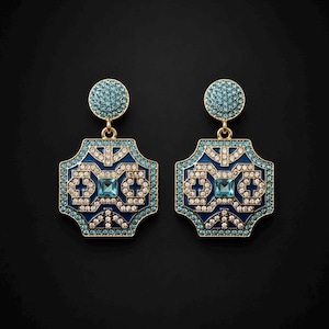 May include: A pair of gold-tone drop earrings featuring a circular stud top covered in light blue crystals. The main pendant is a geometric, octagonal shape with deep blue enamel, light blue crystal borders, and a central square light blue stone.