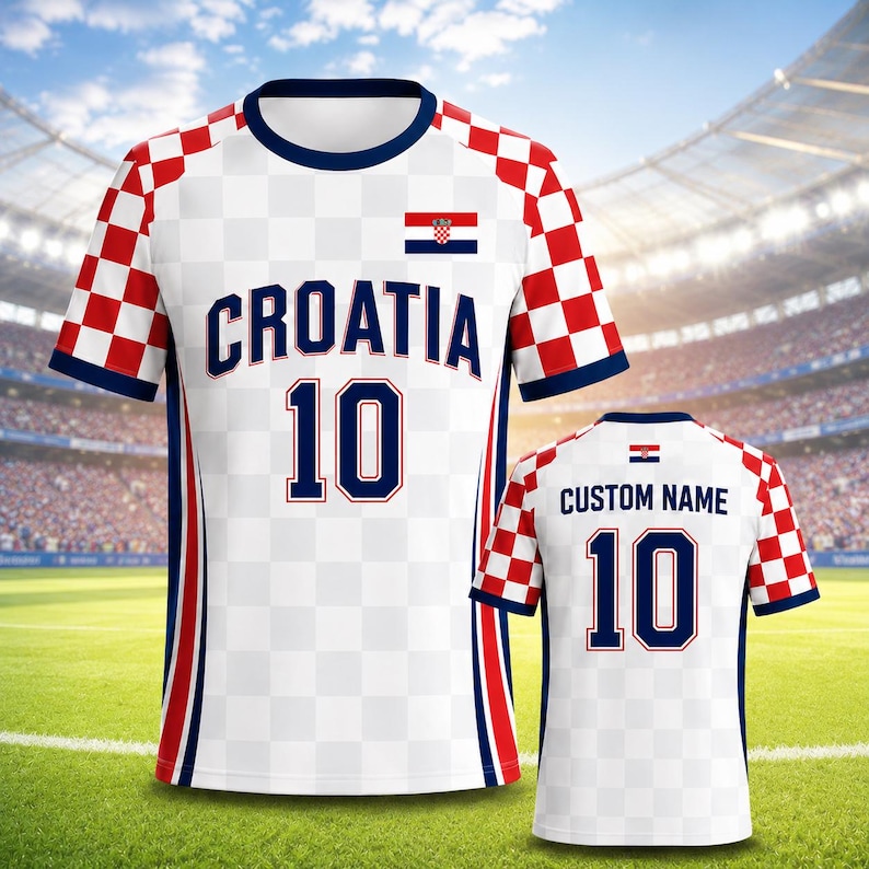 Może przedstawiać: Biała koszulka piłkarska z napisem "CROATIA" i numerem "10" w kolorze granatowym. Koszulka ma czerwono-białe, w kratkę rękawy i chorwacką flagę na piersi. W tle widoczna jest druga koszulka.