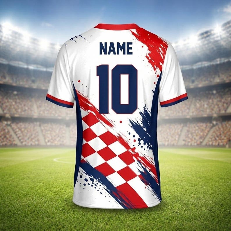 May include: White soccer jersey with red and blue accents, featuring the number 10 in navy blue. The jersey has a Croatian checkerboard pattern and the word "NAME" above the number. The design includes brushstroke-style graphics.