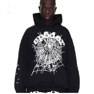 Peut inclure: Sweat &agrave; capuche noir avec un motif de toile d'araign&eacute;e blanche et le mot "sp5der". Les manches sont orn&eacute;es d'&eacute;toiles blanches. Le sweat &agrave; capuche a une capuche et une coupe ample.