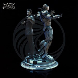 May include: A detailed statue featuring two figures: a man in a suit and an Iron Man suit. The figures are positioned back-to-back on a circular base. The statue is predominantly gray and black, with the text "Jansen Figures" in the upper left corner.