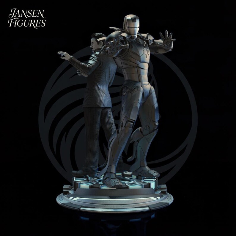 May include: A detailed statue featuring two figures: a man in a suit and a metallic Iron Man suit. The figures stand on a circular base with a geometric pattern. The statue is predominantly silver and black, with the text "Jansen Figures" in the upper left corner.