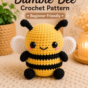 May include: A crocheted bumble bee with yellow and black stripes, white wings, and black antennae. The text "Bumble Bee Crochet Pattern" and "Beginner Friendly" are displayed above the bee. The bottom of the image displays "AmanCrochyPatterns".