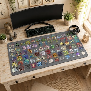May include: A large rectangular desk mat featuring a gray background covered in a grid of colorful, stylized monster icons. The design includes various creature illustrations, symbols, and a question mark icon, all arranged in a structured pattern.