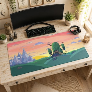 May include: A rectangular desk mat featuring a colorful cartoon landscape illustration. The scene depicts a large green treehouse structure set against a sunset sky with shades of pink and orange, alongside jagged purple mountains and rolling green hills.
