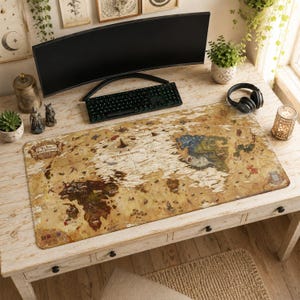 Puede incluir: Alfombrilla de escritorio rectangular con un diseño de mapa del mundo vintage en tonos beige, marrón y azul. La alfombrilla está sobre un escritorio blanco con un teclado, monitor y auriculares negros. El texto "The Tears of the Kingdom" es visible.