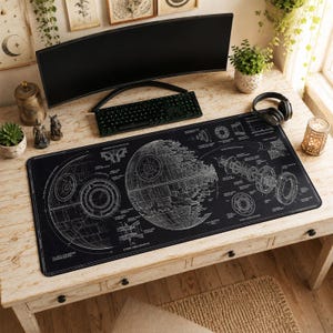May include: A rectangular black desk mat featuring a white technical blueprint illustration of the Death Star. The design includes detailed cross-section diagrams, structural schematics, and various technical labels printed across the surface.