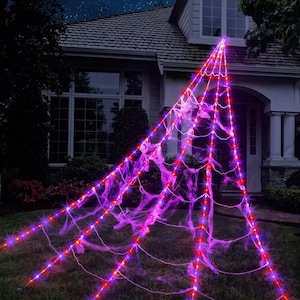 Op de afbeelding: Een driehoekige buitenverlichting in de vorm van een spinnenweb, voorzien van heldere paarse en rode ledlampjes in een stralend patroon. De structuur is gedrapeerd met dun, wazig paars webmateriaal voor een lichtgevend effect.