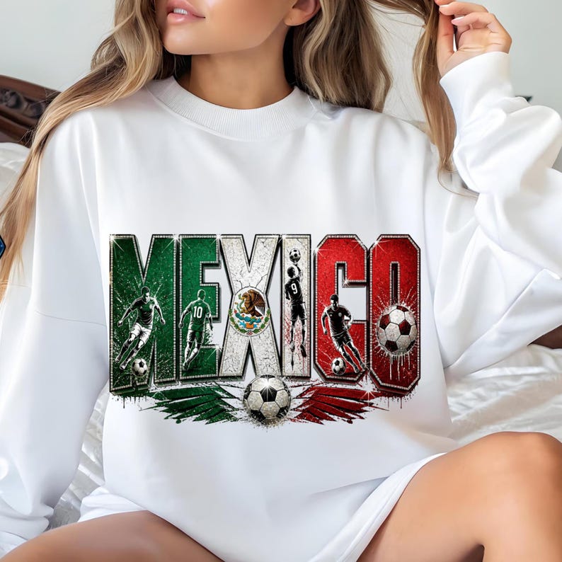 May include: A white long-sleeve sweatshirt featuring a large graphic print of the word MEXICO in green, white, and red block letters. The design includes illustrations of soccer players, a soccer ball, and the Mexican coat of arms emblem.