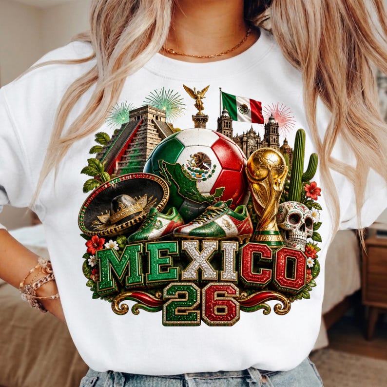 May include: A white sweatshirt featuring a graphic print of Mexican cultural symbols including a soccer ball, a trophy, a sombrero, a skull, a cactus, a pyramid, and the Mexican flag. The text MEXICO 26 is displayed in large, bold letters.