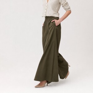 K&ouml;nnte beinhalten: Olivgr&uuml;ne Hose mit weitem Bein und Taschen. Die Hose wird mit einer hellen, gekn&ouml;pften Strickjacke und beigen Abs&auml;tzen kombiniert. Die Hose hat eine hohe Taille und ein flie&szlig;endes, ausgestelltes Design. Die Abs&auml;tze sind spitz und haben einen Stilettoabsatz.