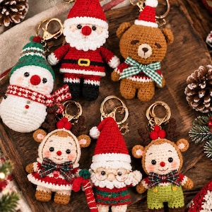Può includere: Un set di sei portachiavi all'uncinetto a tema natalizio che raffigurano un pupazzo di neve, Babbo Natale, un orsetto con fiocco a quadri verdi, una renna, uno gnomo di Babbo Natale con occhiali e una renna, con anelli in metallo dorato.