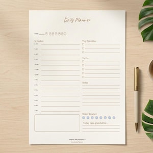 Puede incluir: Una hoja de planificador diario con un horario de 6 AM a 7 PM, secciones para prioridades, lista de tareas, notas, un rastreador de agua con ocho círculos y un espacio de gratitud. El encabezado dice Daily Planner y al pie Projects, not perfection.