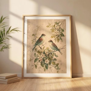 May include: A framed wall art print featuring two birds perched on flowering branches against a textured beige background. The birds have brown and blue-grey plumage, surrounded by green leaves and white blossoms in a detailed painterly style.