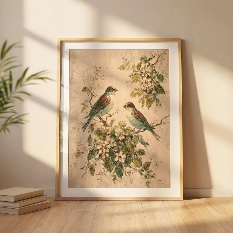 May include: A framed wall art print featuring two birds perched on flowering branches against a textured beige background. The birds have brown and blue-grey plumage, surrounded by green leaves and white blossoms in a detailed painterly style.
