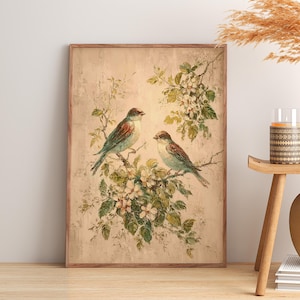 May include: A rectangular wall art print featuring a painting of two birds perched on flowering branches. The birds have brown and blue-green plumage, and the blossoms are white with green leaves. The background is a textured, light beige colour.