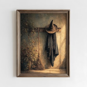 May include: A framed wall art print depicting a dark pointed hat and a long black cloak hanging from a wooden rack. Beside the rack stands a tall straw broom, and a leafy green plant is positioned to the left, all set against a textured wall.