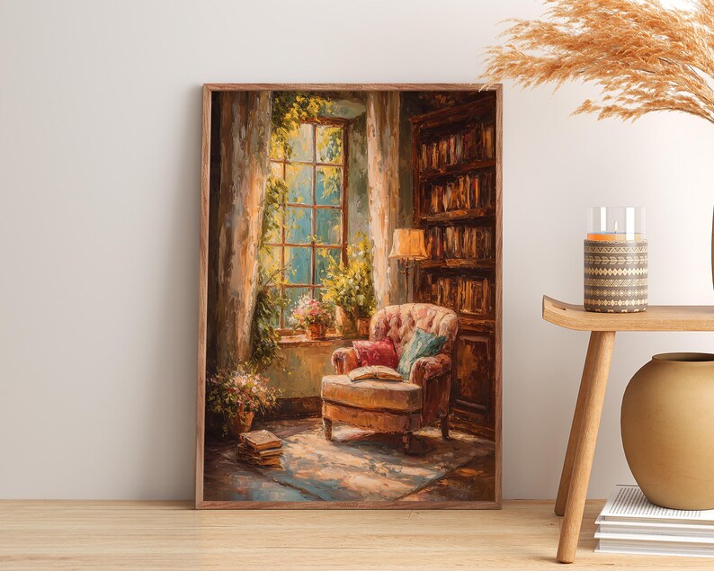May include: A framed art print depicts a cozy reading nook. An upholstered armchair with a book sits near a window with plants. A bookshelf and a lamp are also visible, creating a warm, inviting atmosphere. The artwork is in a warm color palette.