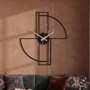 Könnte beinhalten: Eine Wanduhr aus schwarzem Metall mit einem geometrischen Design aus zwei Halbkreisbögen und vertikalen Linien. Die Uhr hat ein kreisförmiges Zentrum mit dünnen, hellen Zeigern. Die Struktur ist an einer Wand montiert und zeigt eine lineare Optik.