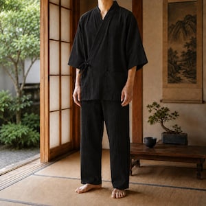 Puede incluir: Conjunto negro estilo kimono, compuesto por una bata y pantalones a juego. La bata tiene un diseño envolvente con cierre de lazo y mangas cortas. Los pantalones son holgados. El conjunto es de tejido texturizado. Interior japonés tradicional.