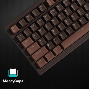 May include: A mechanical keyboard featuring a two-tone brown color scheme with dark brown and lighter brown keycaps. The keys display white lettering for standard QWERTY layout characters, function keys, and control commands. MancyCaps logo is visible.