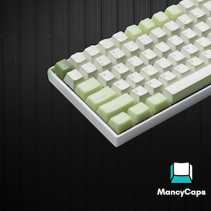 May include: A mechanical keyboard featuring a white frame and a gradient keycap set that transitions from white to light green. The keys display standard QWERTY lettering in a dark font. A logo with the text MancyCaps is visible in the corner.