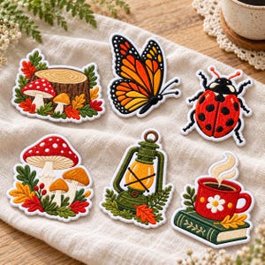 May include: Six embroidered patches featuring a tree stump with mushrooms, a monarch butterfly, a ladybug, a cluster of mushrooms, a green lantern, and a red mug with a white flower on a green book, all with white borders.