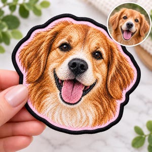 May include: A circular embroidered patch featuring a detailed portrait of a golden-colored dog with a white muzzle and chest, a black nose, and an open mouth with a pink tongue. The patch has a light pink border and a thick black outer edge.