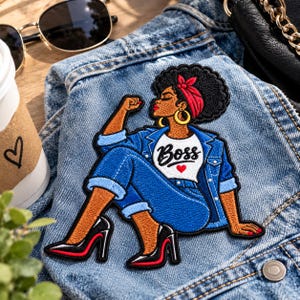 May include: An embroidered patch featuring a person with dark skin and a large afro hairstyle wearing a red headband, a white t-shirt with the text Boss and a red heart, a blue denim jacket, blue jeans, and black high-heeled shoes with red soles.
