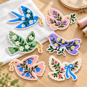 May include: Six embroidered bird patches featuring various designs: a blue bird with white flowers and a gold key, a peach bird with purple flowers, a green bird with white flowers and a gold key, a purple bird with yellow flowers, a peach bird with blue flowers and a gold key, and a cream bird with pink flowers and a blue ribbon.