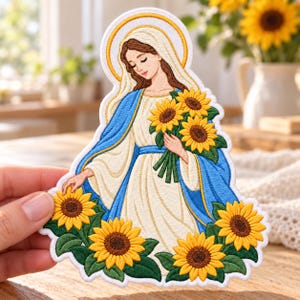 May include: An embroidered patch featuring a figure with long brown hair wearing a white head covering and a blue cloak over a white dress. The figure holds a bouquet of yellow sunflowers, with additional sunflowers at the base.