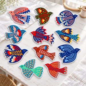 May include: A collection of ten embroidered bird patches featuring various color combinations including red, blue, green, and orange. Each patch displays intricate floral and geometric patterns stitched onto fabric with a white border outline.
