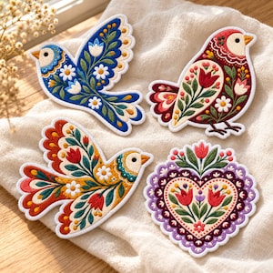 May include: Four embroidered fabric patches featuring intricate floral and bird motifs. One patch is a blue bird, one is a red bird, one is a yellow bird, and one is a heart shape, all decorated with colorful flowers and leaves.