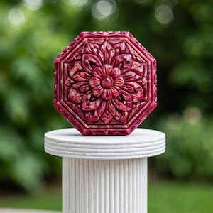May include: A deep magenta octagonal decorative object featuring a detailed, symmetrical floral relief carving on its front surface. The piece displays intricate petal patterns radiating from a central point, with a polished, glossy finish.