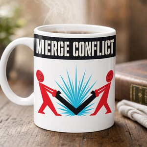Puede incluir: Taza de cerámica blanca con las palabras "MERGE CONFLICT" en letras negras. La taza presenta un gráfico de dos figuras rojas tirando de un objeto negro en forma de V, con líneas azules que irradian hacia afuera. El vapor se eleva de la parte superior de la taza.