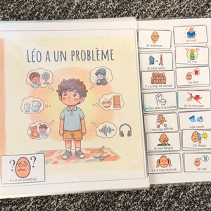 Peut inclure: Un livre à spirales intitulé "LÉO A UN PROBLÈME" avec des illustrations d'un garçon et des symboles représentant des sentiments et des besoins. Le livre comprend une page d'aides visuelles avec des phrases comme "J'ai faim" et "J'ai froid."