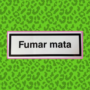 May include: A rectangular sign with the text "Fumar mata" in black, framed by a pink and black border, set against a green leopard print background.