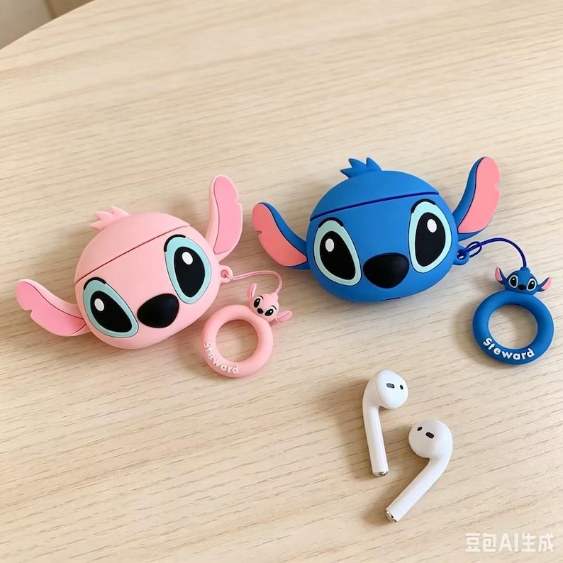 May include: Two silicone earphone cases shaped like cartoon characters, one in light pink and one in blue, each featuring large eyes and side ears. Both cases include a matching circular ring charm with a small character head and the text Steward.