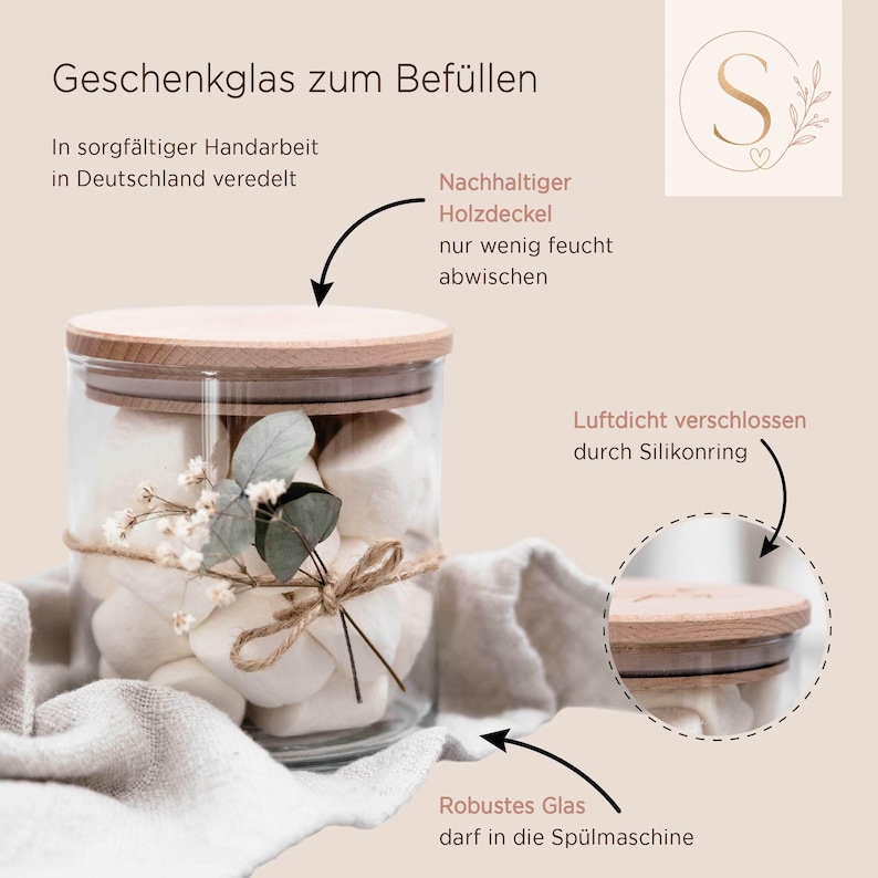 May include: A clear glass storage jar with a light wood lid, filled with white marshmallows. The jar is decorated with a small sprig of dried eucalyptus and baby's breath tied with twine. Text on the image includes Geschenkglas zum Bef&uuml;llen.