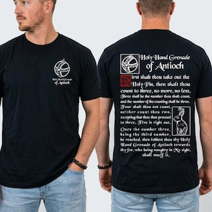 May include: A black t-shirt featuring a white graphic of the Holy Hand Grenade of Antioch on the front left chest. The back displays the same grenade icon, a red square, a rabbit illustration, and the text of the Holy Hand Grenade instructions.