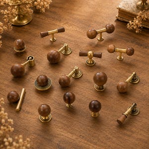 May include: A collection of cabinet hardware featuring various drawer pulls and knobs made from dark brown wood and antique brass metal. The assortment includes T-shaped handles, spherical knobs, and drop pulls with circular mounting plates.