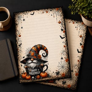 Può includere: Carta da lettere con sfondo crema a righe e bordo nero decorato con ragnatele, pipistrelli e zucche arancioni. Uno gnomo con un cappello a righe siede dentro una tazza nera con la scritta Happy Halloween, circondato da piccole zucche.